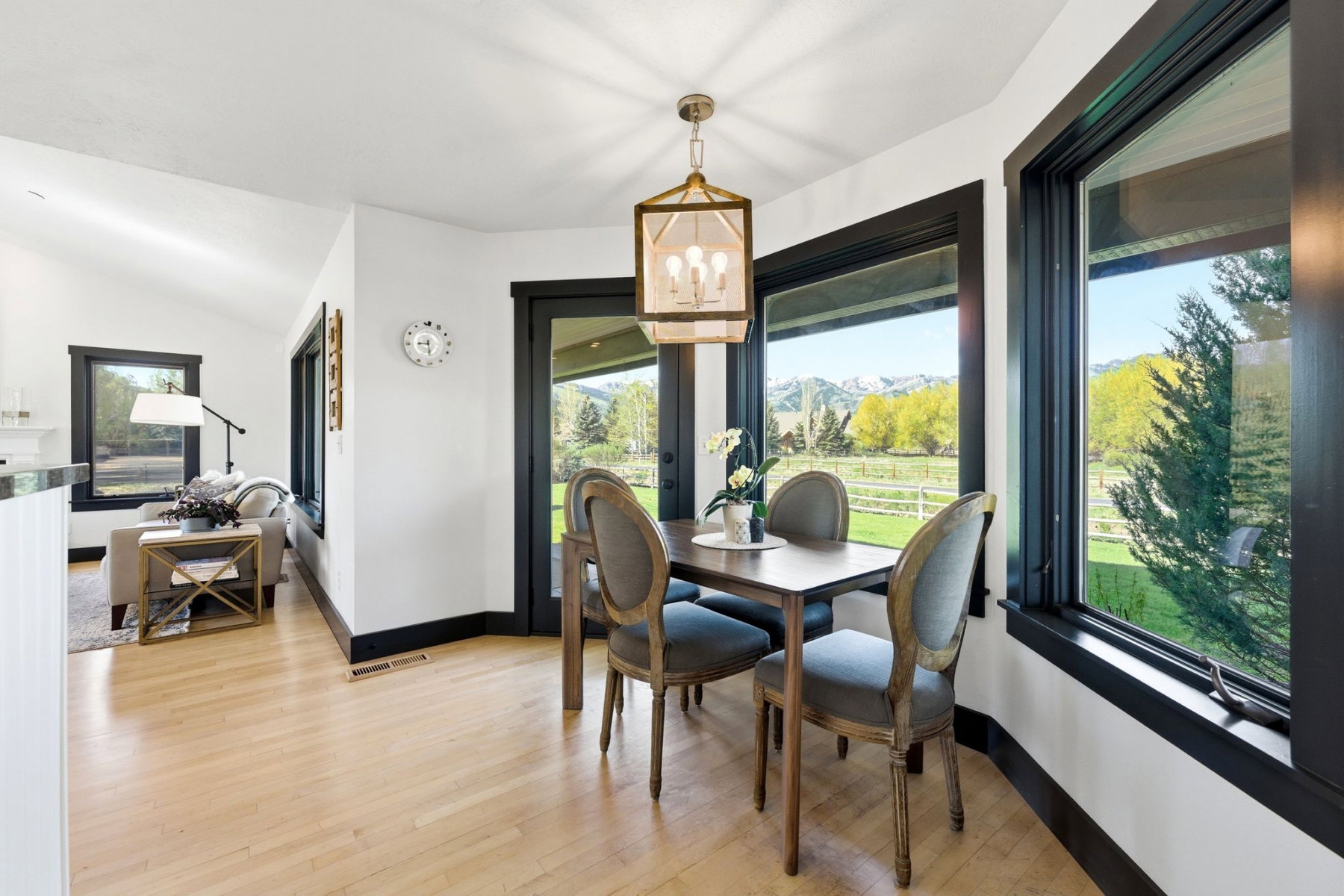 Dining area featuring light wood-finish flooring, a contemporary chandelier, and expansive windows with black trim framing mountain scenery