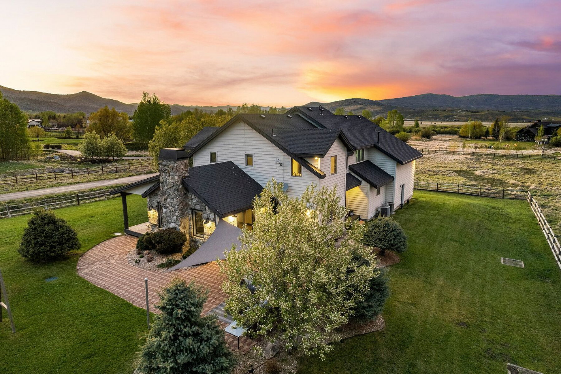 Exterior showcasing a stone chimney, a stone patio with an overhead sunshade, and a covered patio area