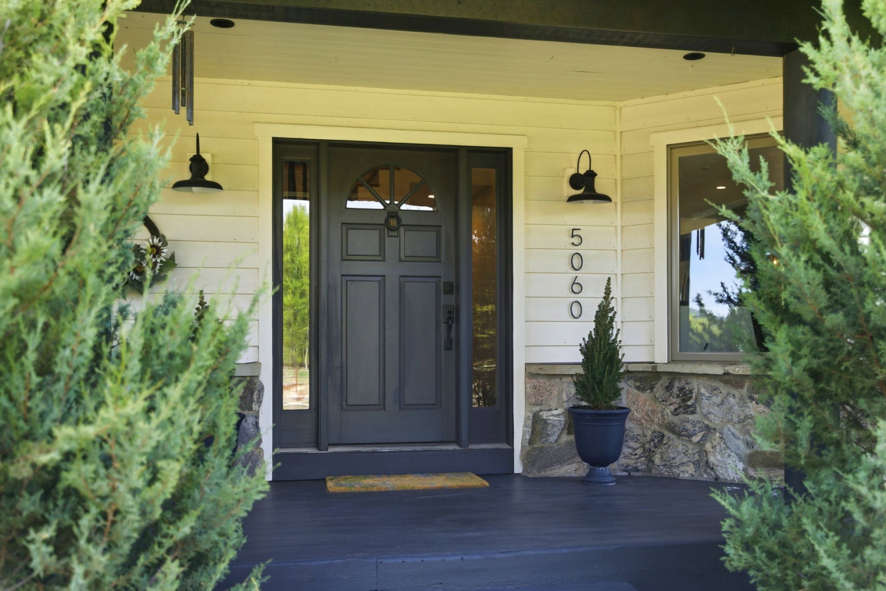 Front entryway featuring a dark painted door with an arched window, sidelight, and decorative knocker