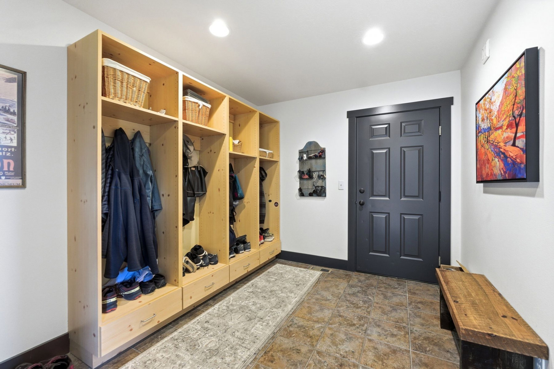 Entryway featuring built-in wood-finish lockers with storage cubbies and drawers, a paneled door with dark trim, recessed lighting, and tile flooring
