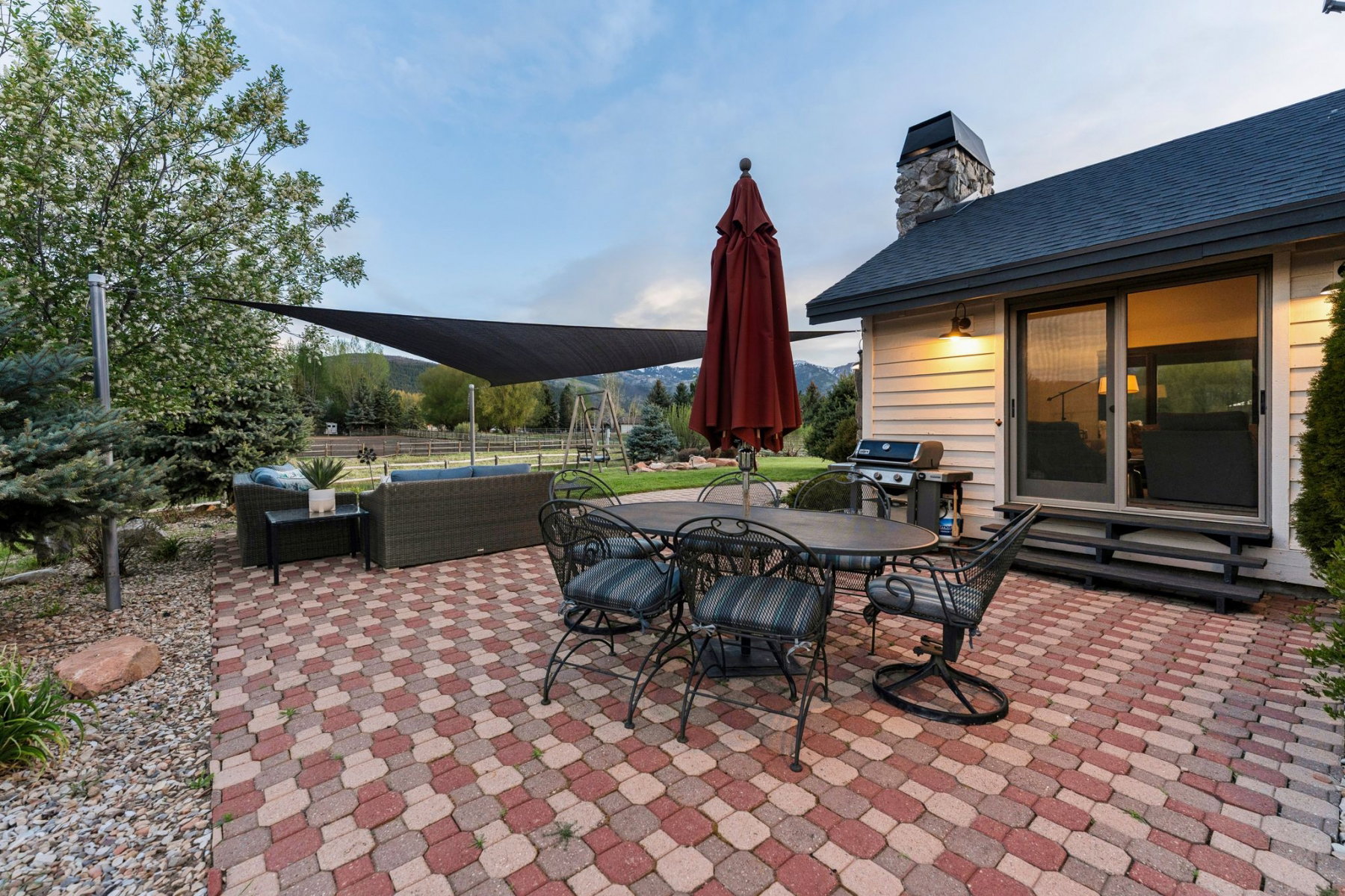 Expansive paver patio with a sun shade, offering a dedicated outdoor living area