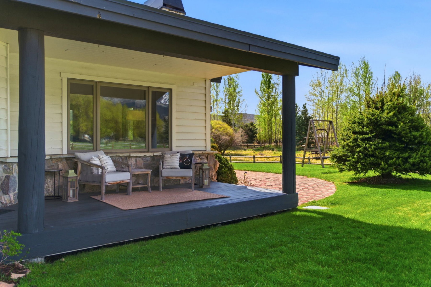 Covered porch with dark-painted posts and a stone veneer foundation