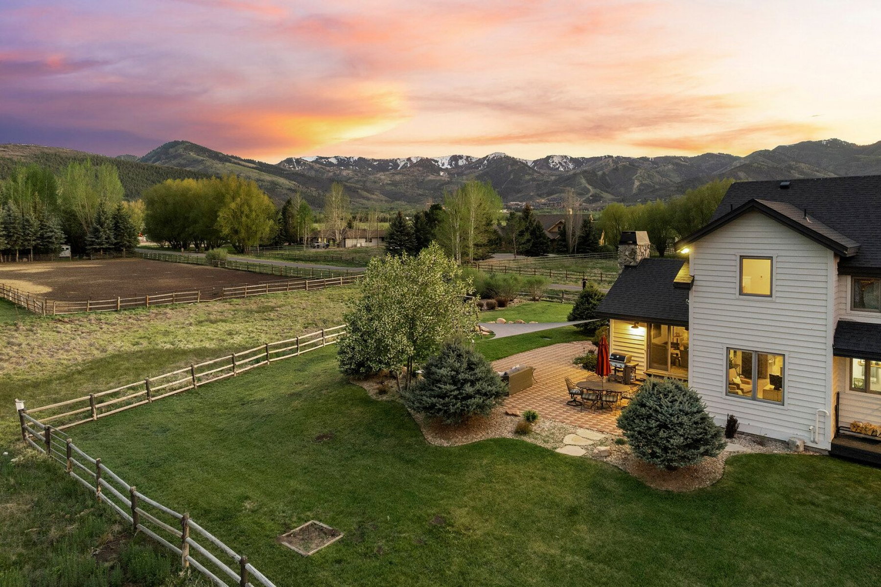 Expansive backyard featuring a manicured lawn, established trees, and a split-rail fence