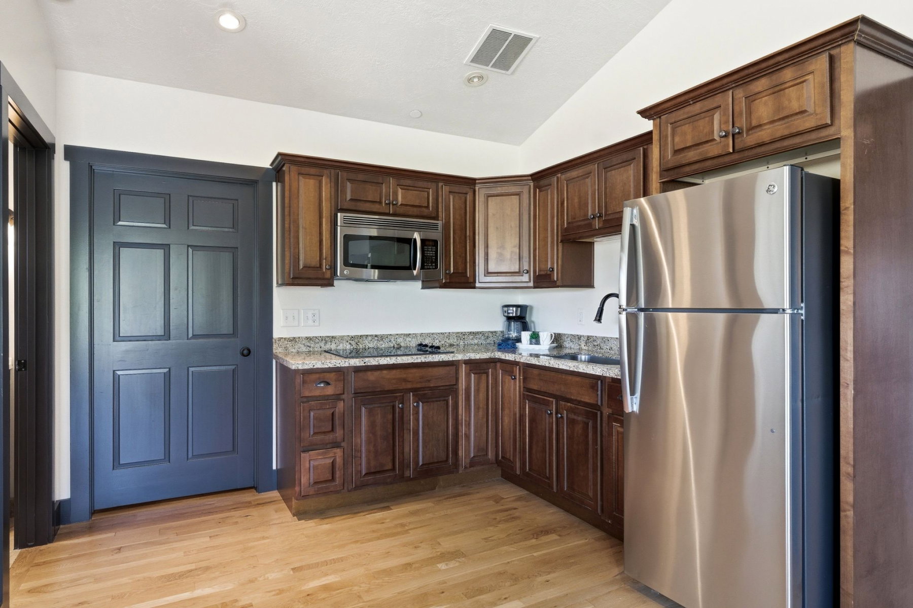 Kitchen featuring wood-finish flooring, dark wood cabinetry, and speckled granite countertops