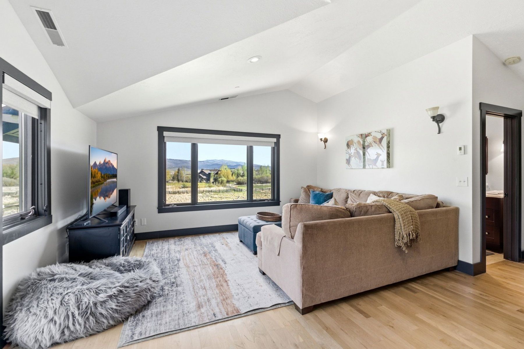 Bright living area featuring light wood-finish flooring and a vaulted ceiling