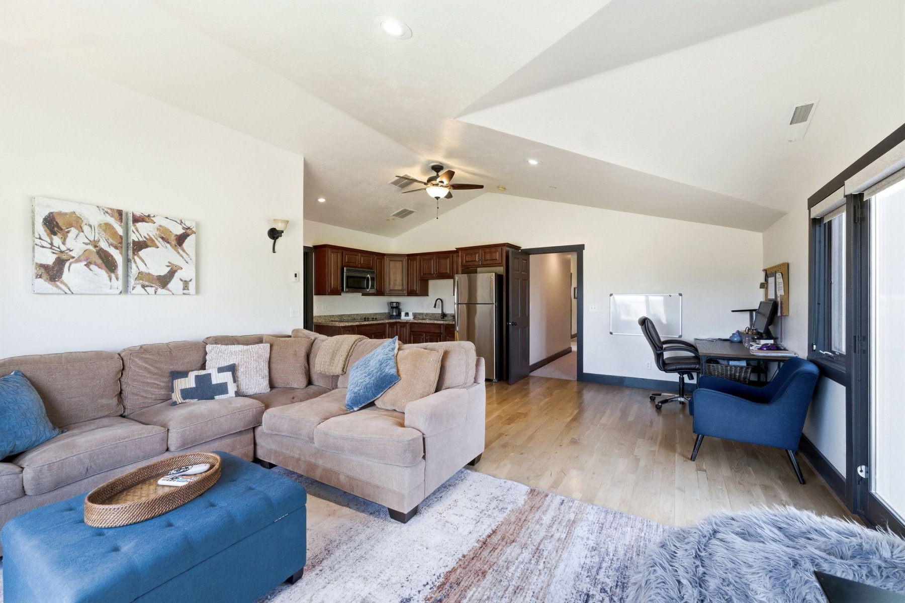 Expansive open-concept living area featuring a vaulted ceiling and wood-finish flooring