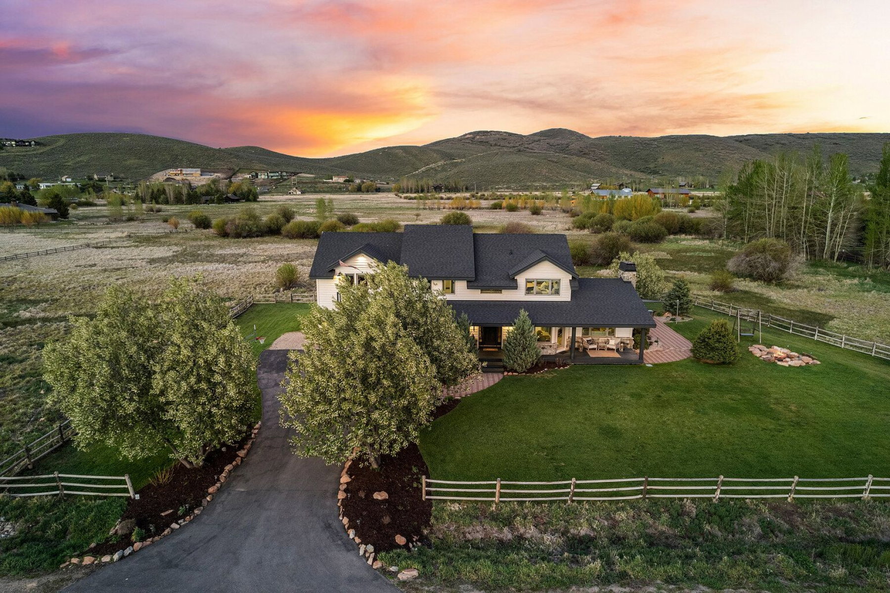Expansive property featuring a two-story residence with a dark shingle roof and a covered porch