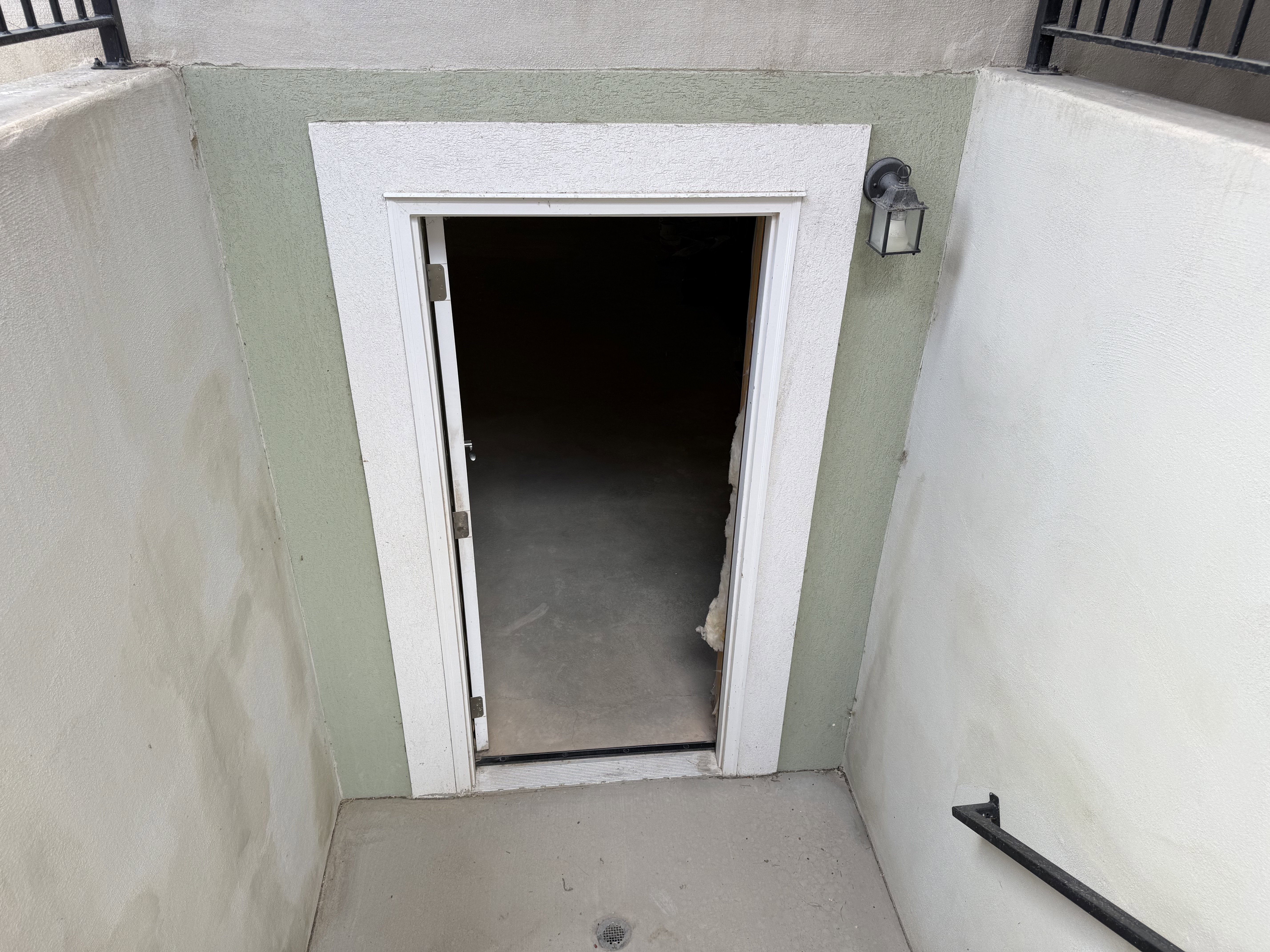 Recessed entryway featuring a painted stucco finish, white door casing, and a black exterior wall sconce