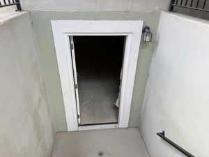 Recessed entryway featuring a painted stucco finish, white door casing, and a black exterior wall sconce