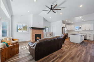 Custom built ADU/Open-concept living space featuring wood-finish flooring, a brick-surround fireplace with a dark wood mantle, and white plantation shutters on multiple windows