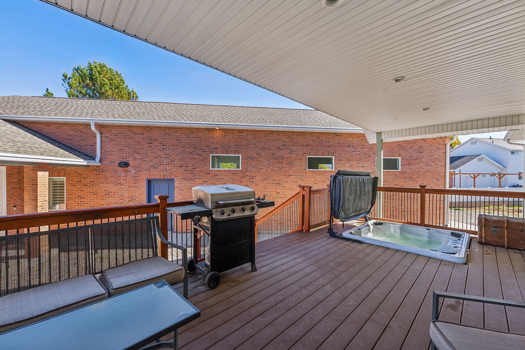 Spacious outdoor deck featuring composite decking, wood railing, and an integrated spa
