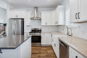 Custom built ADU/Modern kitchen featuring white shaker cabinetry, stainless steel appliances, wood-finish flooring, a farmhouse sink, and light-toned countertops