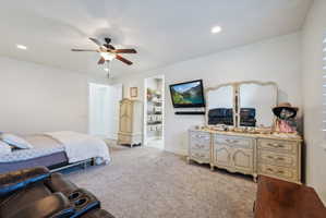 Spacious carpeted room featuring a ceiling fan with integrated lighting, recessed lighting, and a walk-in closet with built-in shelving