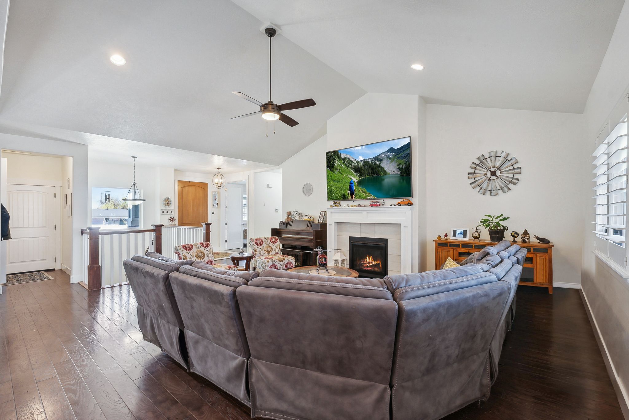 Vaulted ceilings enhance the living area, featuring wood-finish flooring and a corner fireplace with a white mantel