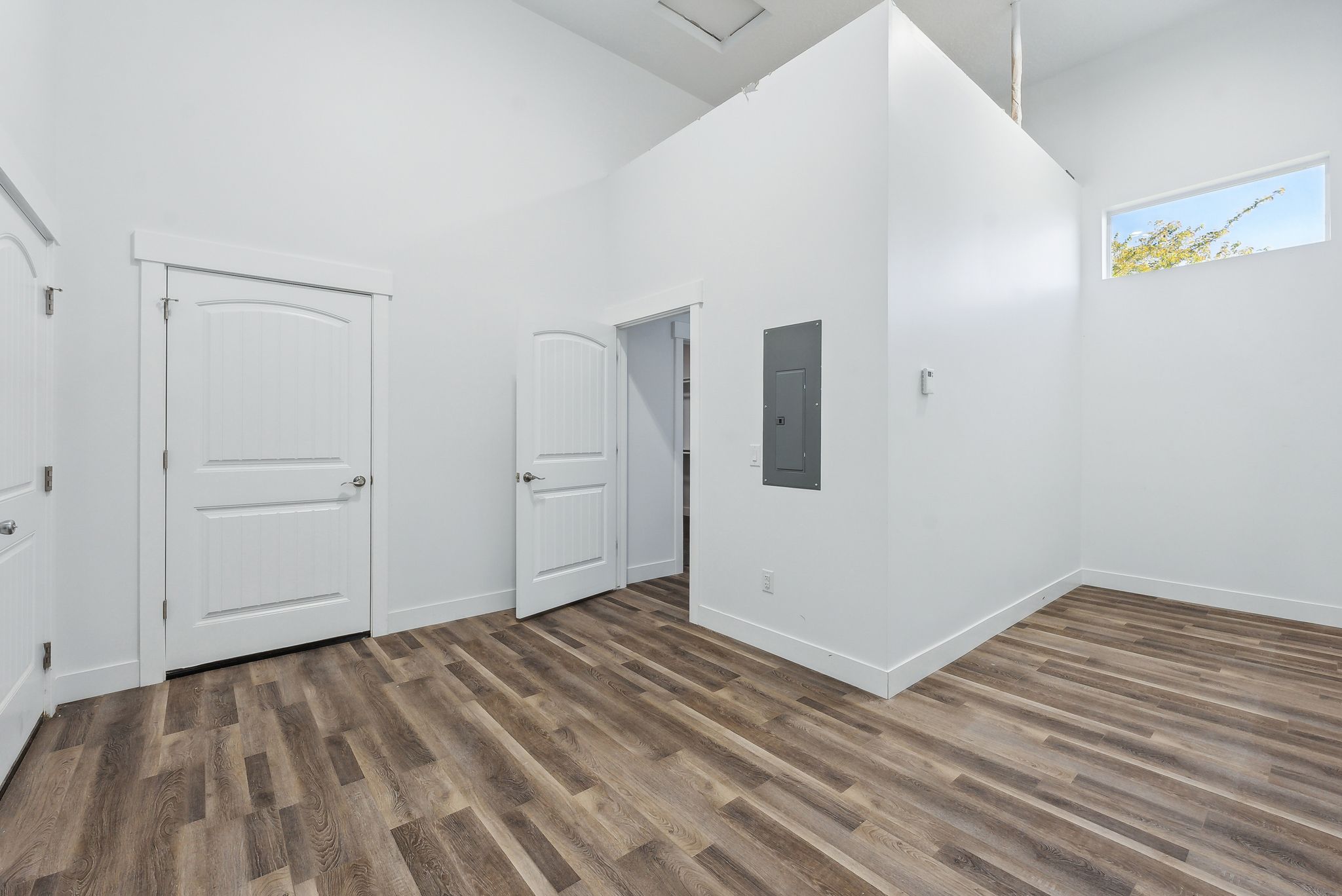 Custom built ADU/Spacious room featuring vaulted ceilings, wood-finish flooring, crisp white walls, and multiple paneled doors