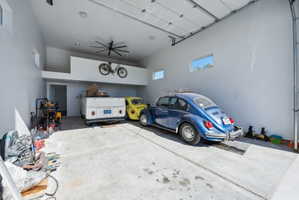 ADU / 4 car/Spacious garage featuring a large overhead door, concrete flooring, high ceilings, an integrated storage loft, and transom windows