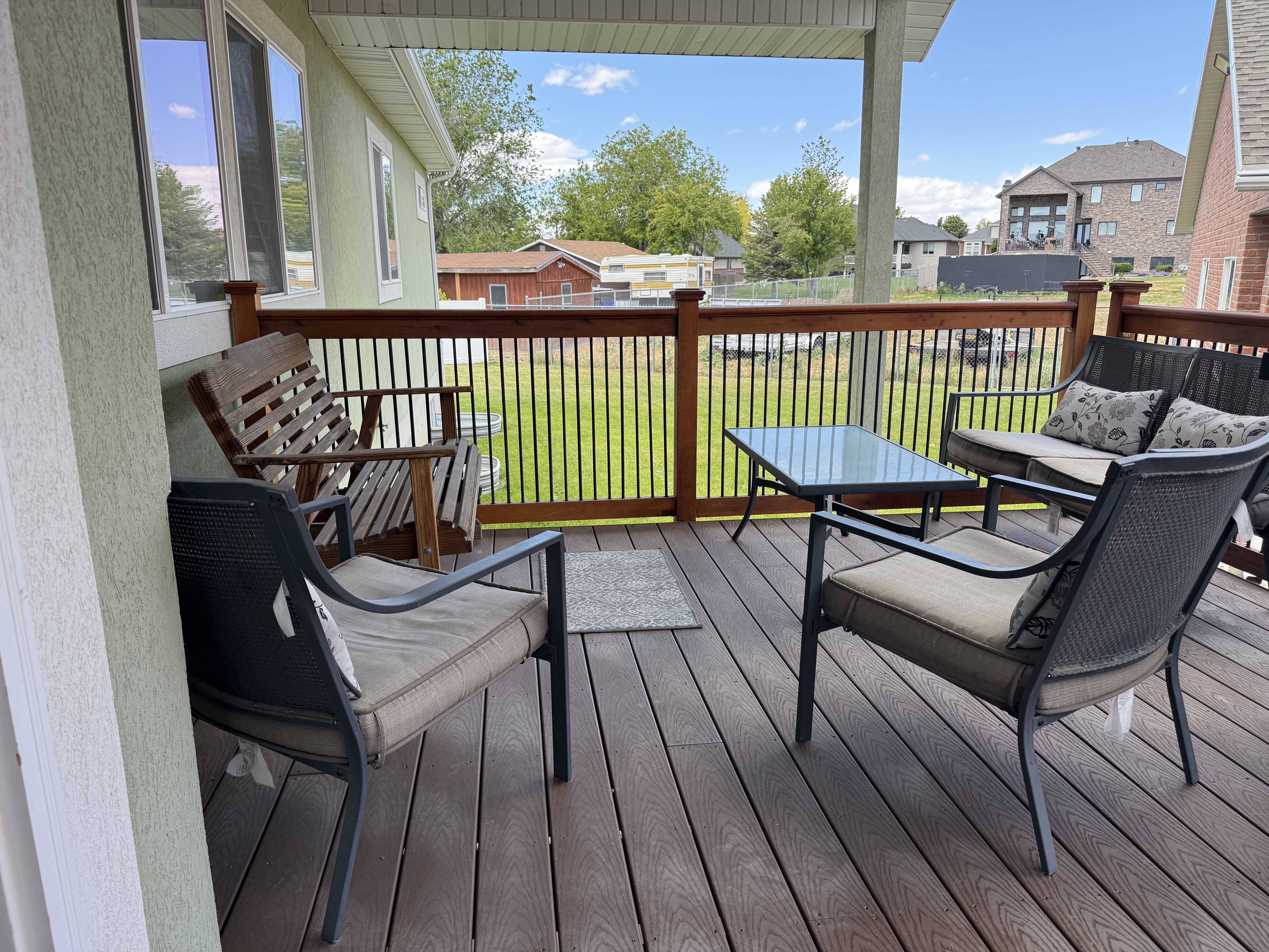 Expansive covered deck featuring composite decking and a wooden railing with black metal balusters