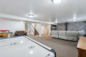 Finished basement space featuring carpeted flooring, a stone-accented wall, recessed lighting, and a built-in entertainment center