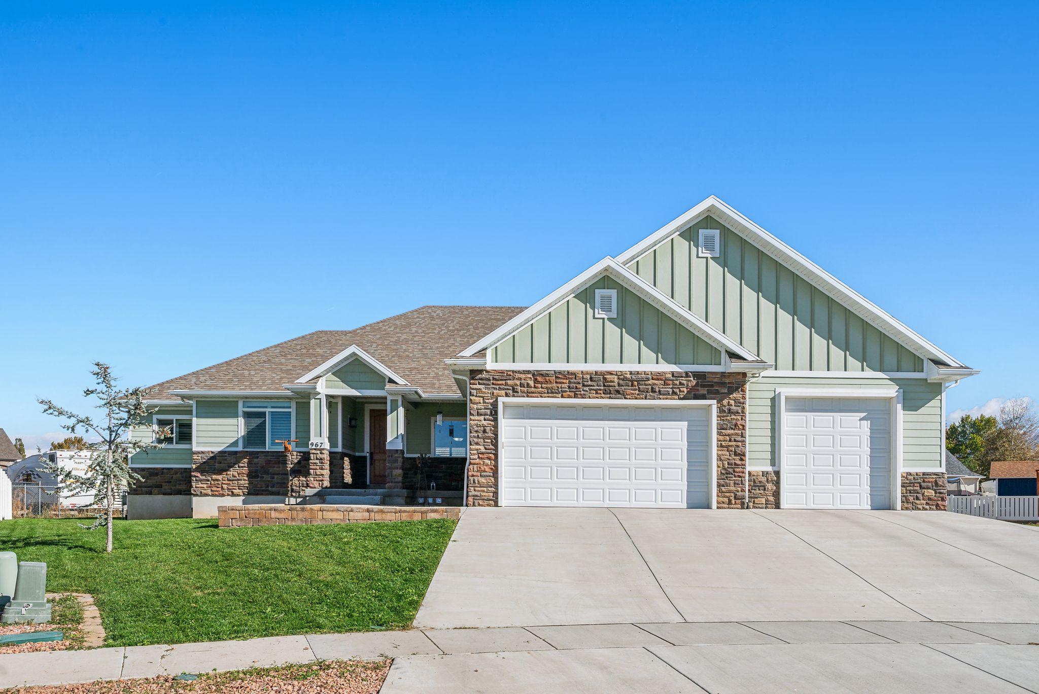 Contemporary home with light green siding and stone veneer accents