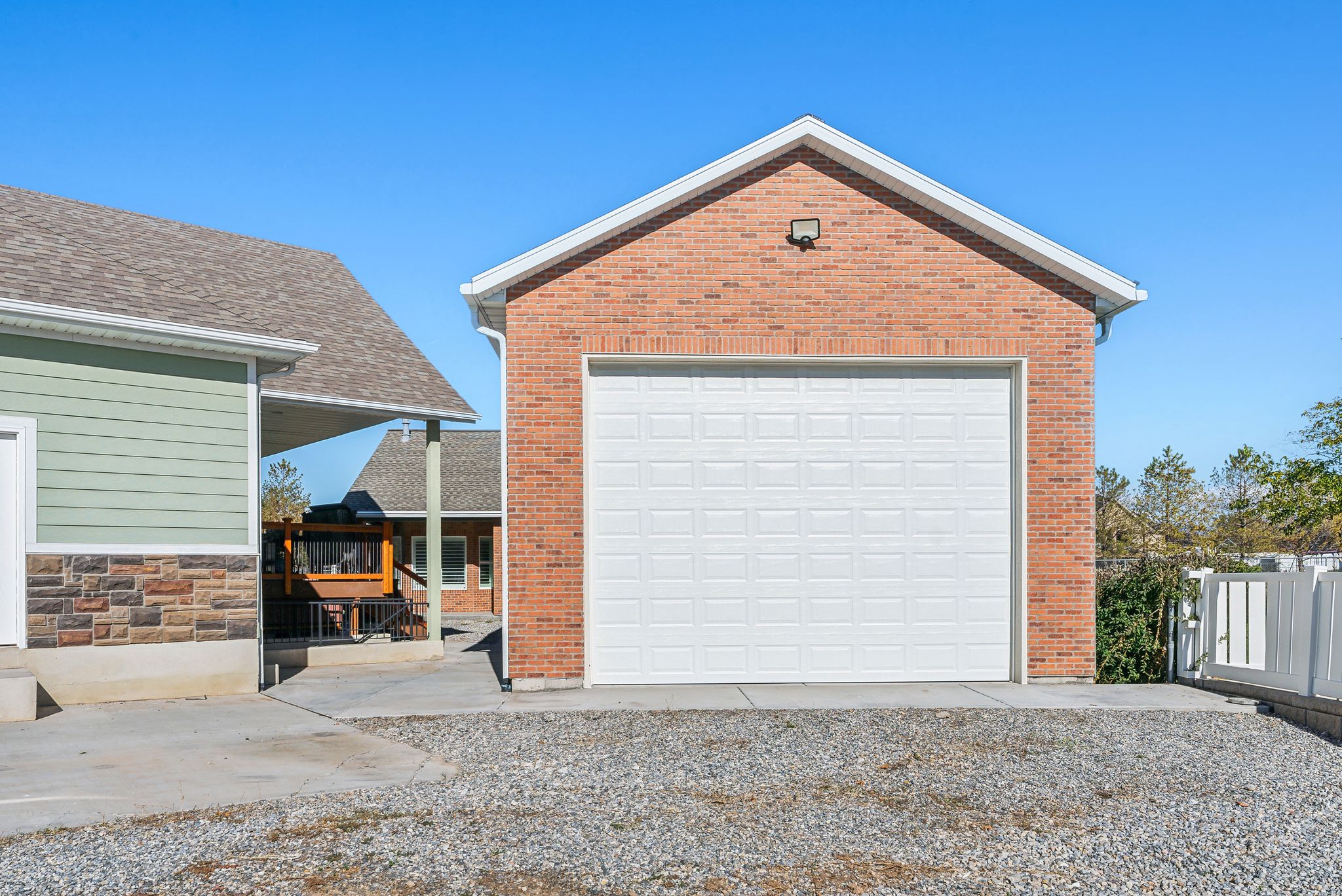ADU/ Brick garage structure featuring a white panel garage door and an exterior light fixture