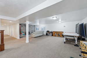 Expansive lower-level space featuring carpet flooring, recessed lighting, and a stone-clad fireplace