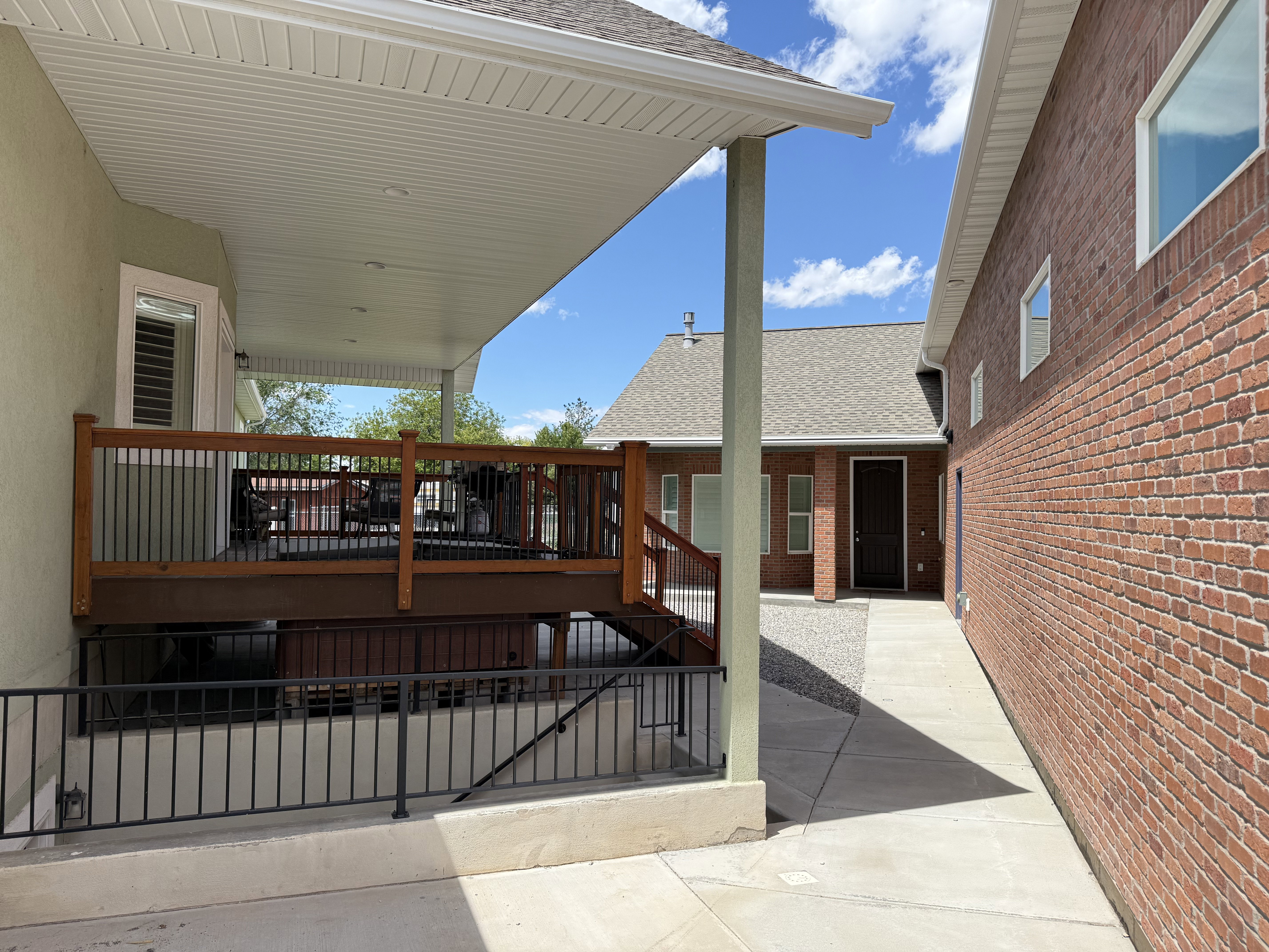 Covered patio with a wood-finish railing and black metal balusters