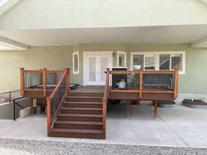 Lower-level deck featuring wood-finish railings with black balusters, providing access to the concrete patio