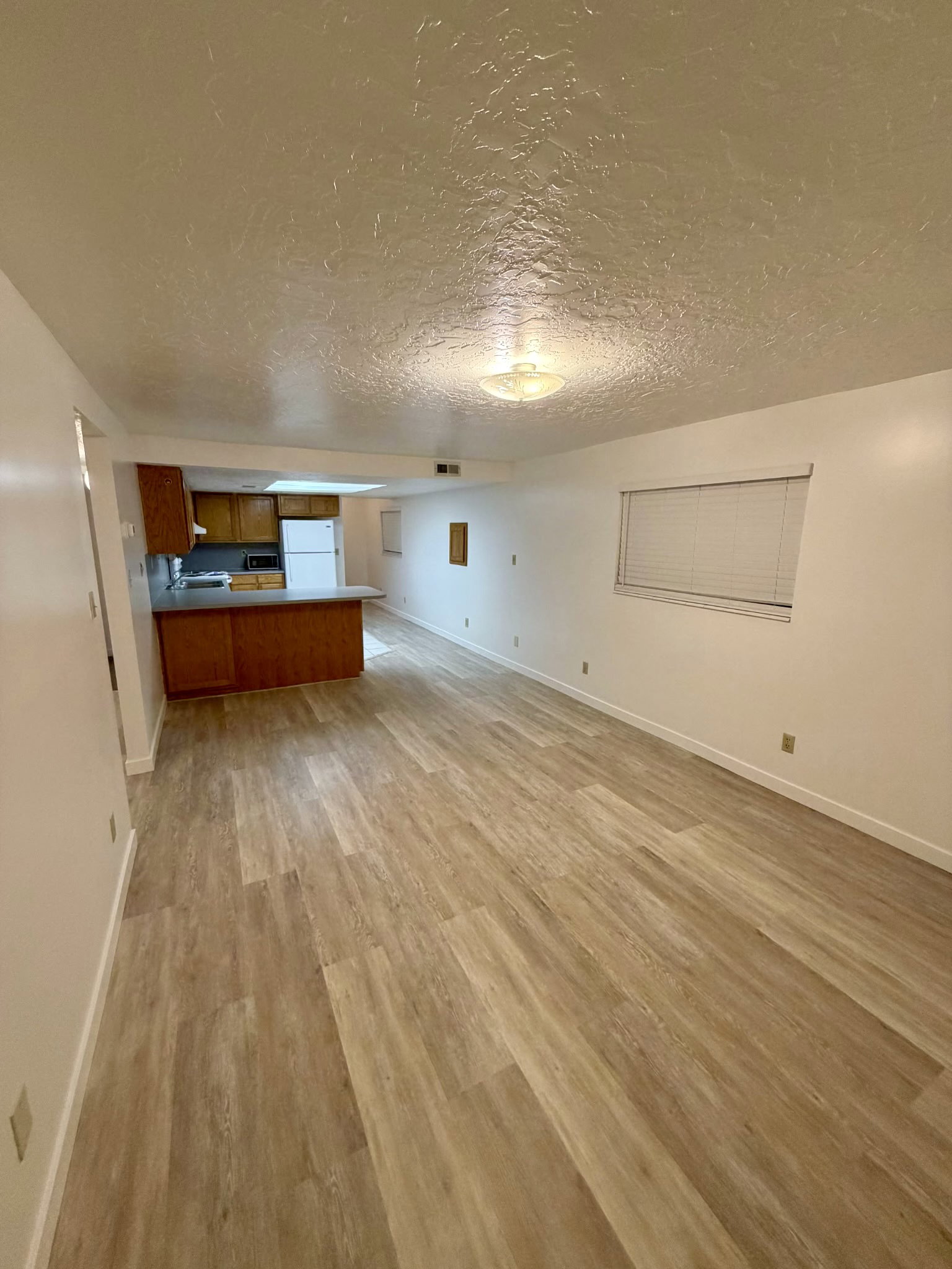 Open-concept living area featuring wood-finish flooring, recessed lighting, and a kitchen with wood cabinetry and a breakfast bar