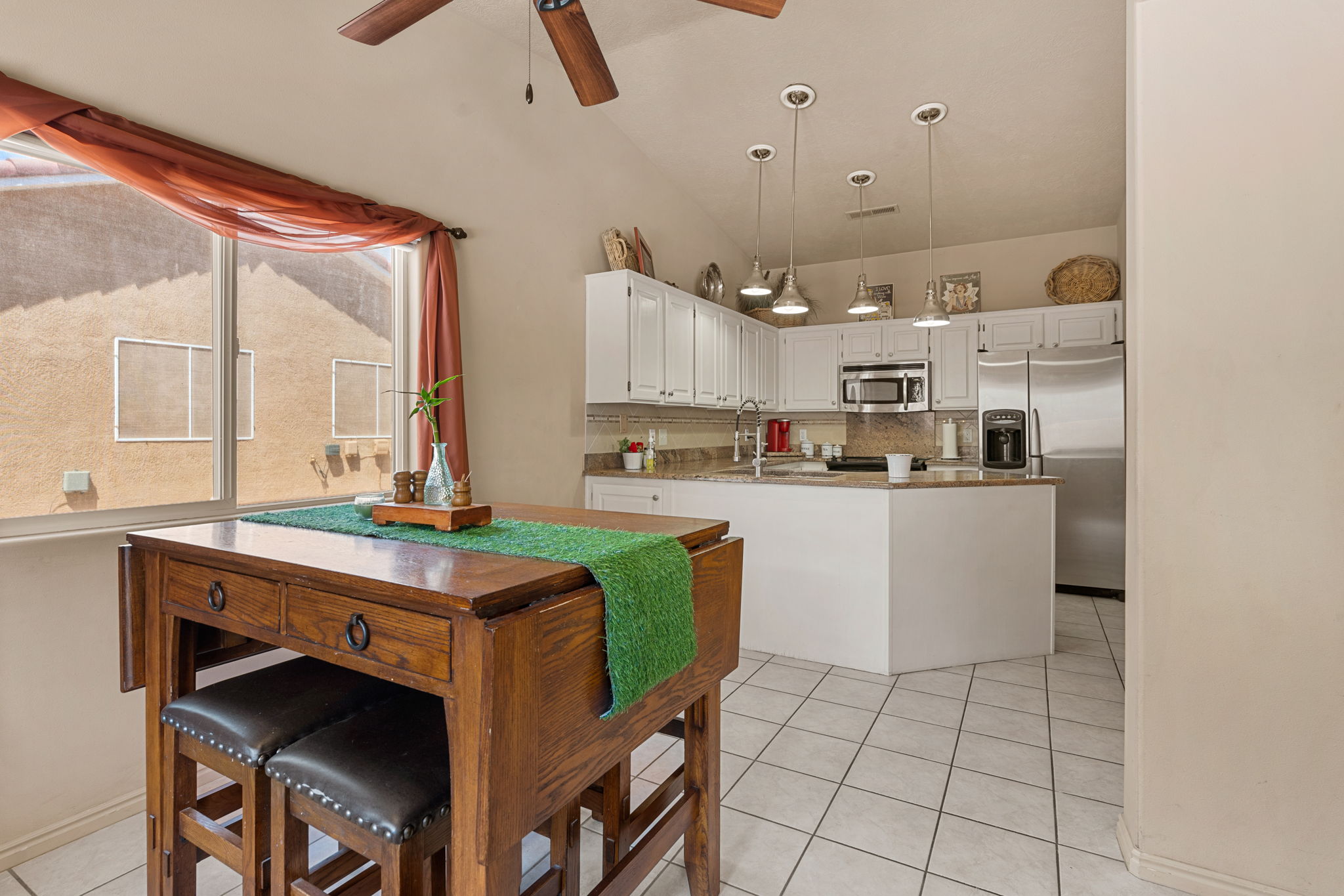 Open-concept kitchen featuring white cabinetry, granite countertops, and stainless steel appliances