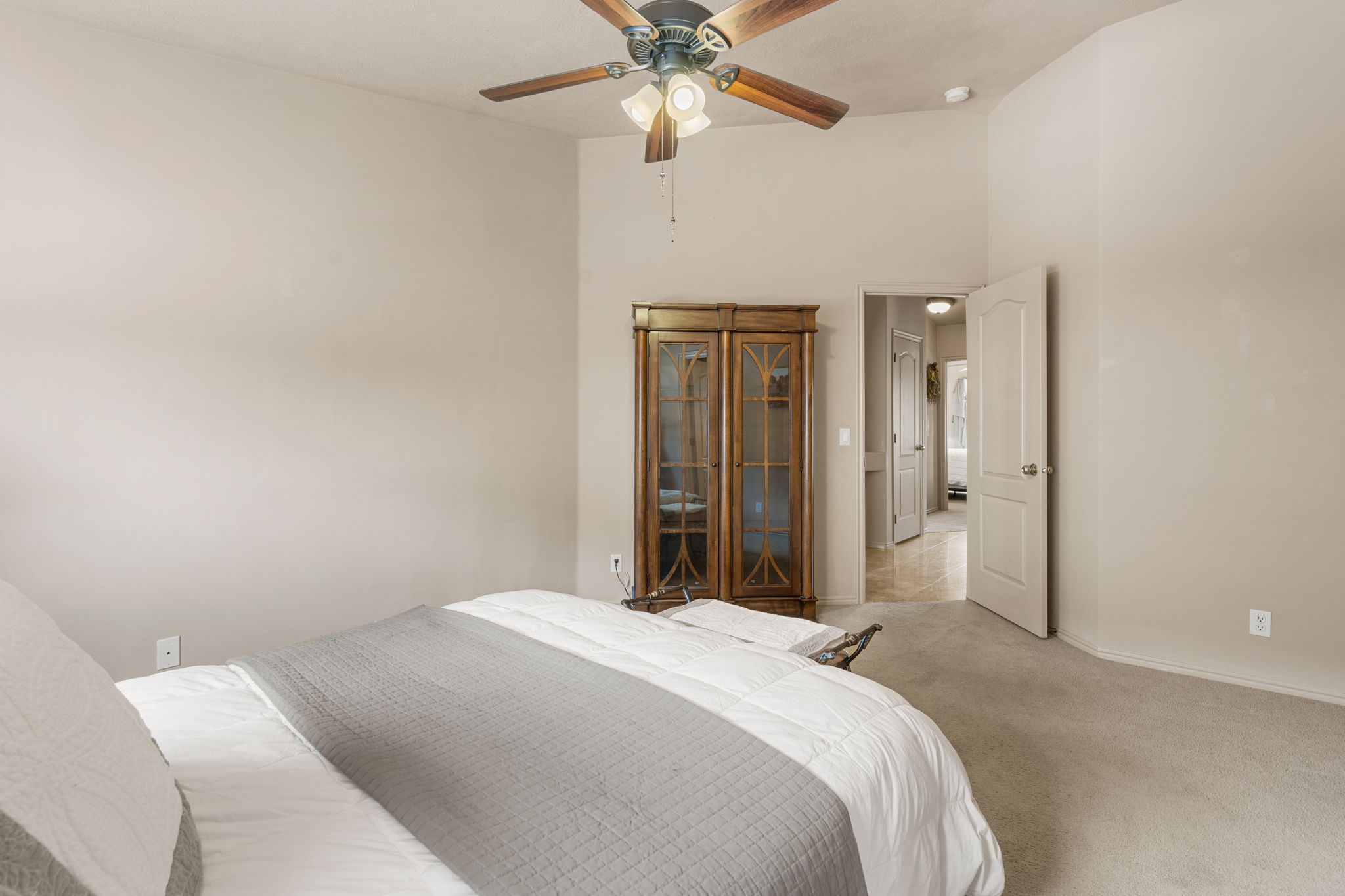 Vaulted ceiling bedroom featuring a ceiling fan with integrated lighting, neutral wall tones, and carpet flooring