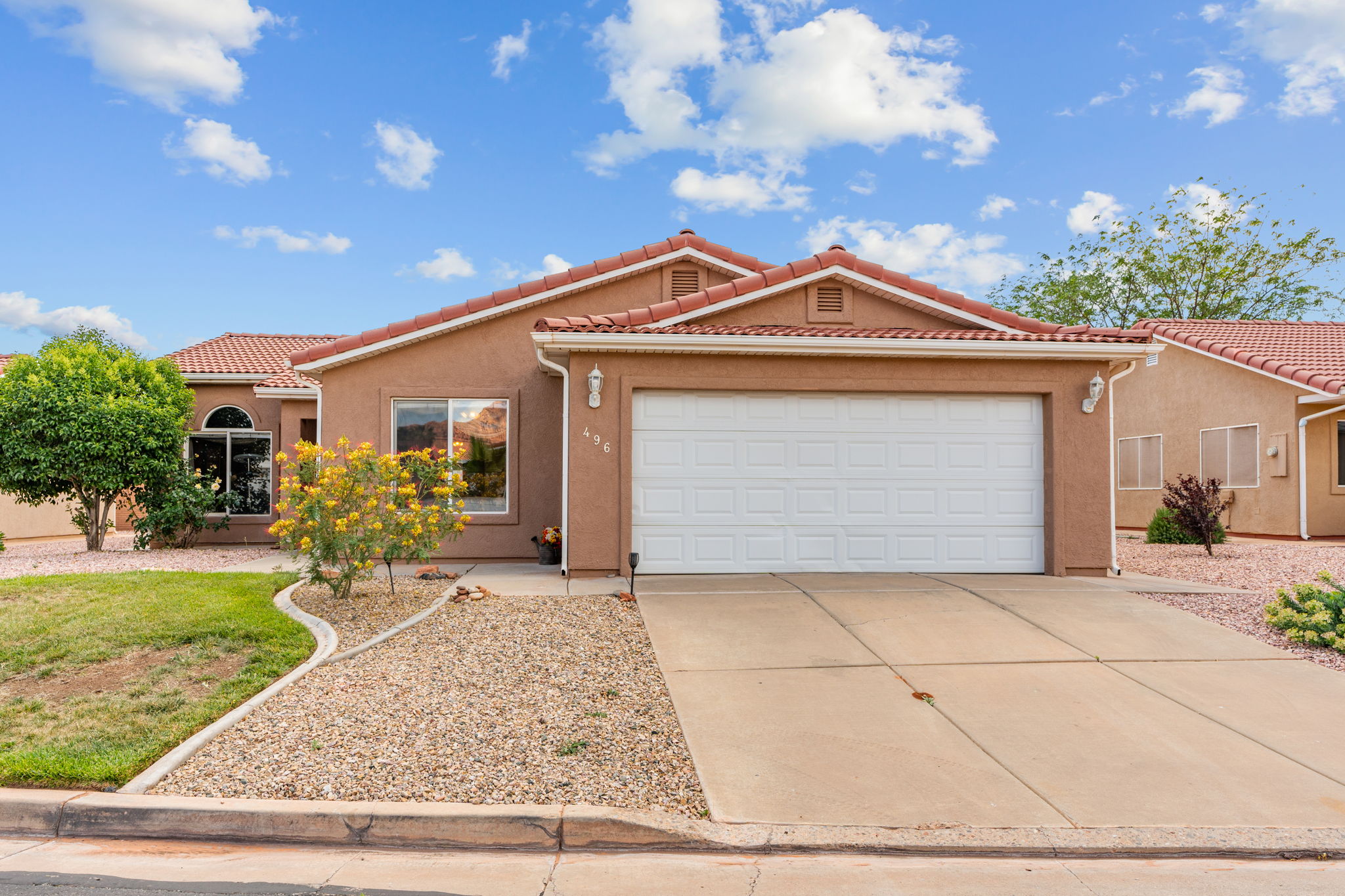 Stucco exterior with a terracotta tile roof, featuring an integrated two-car garage