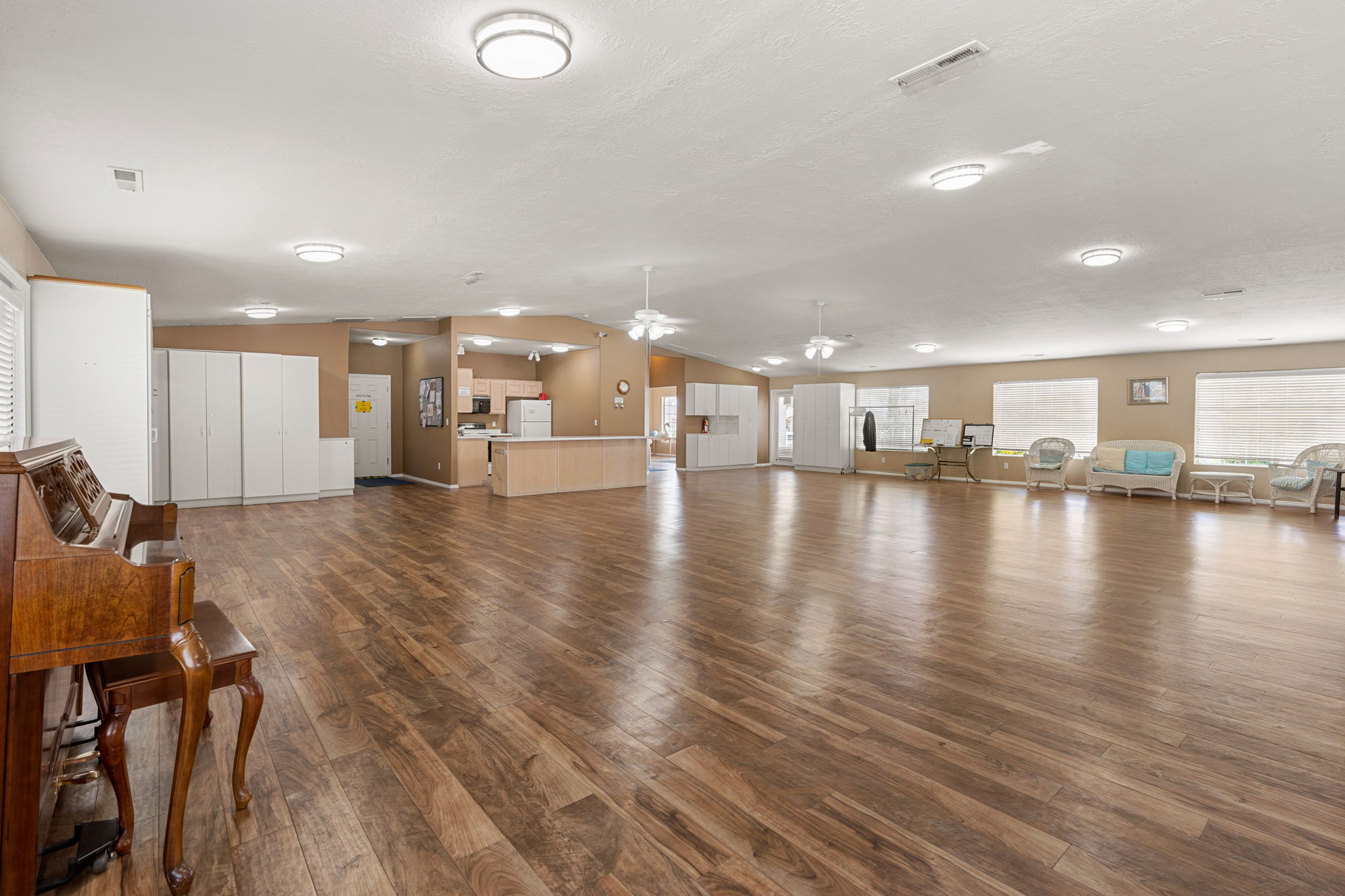 Spacious open-concept room featuring wood-finish flooring, ample built-in white cabinetry, and multiple flush-mount ceiling lights