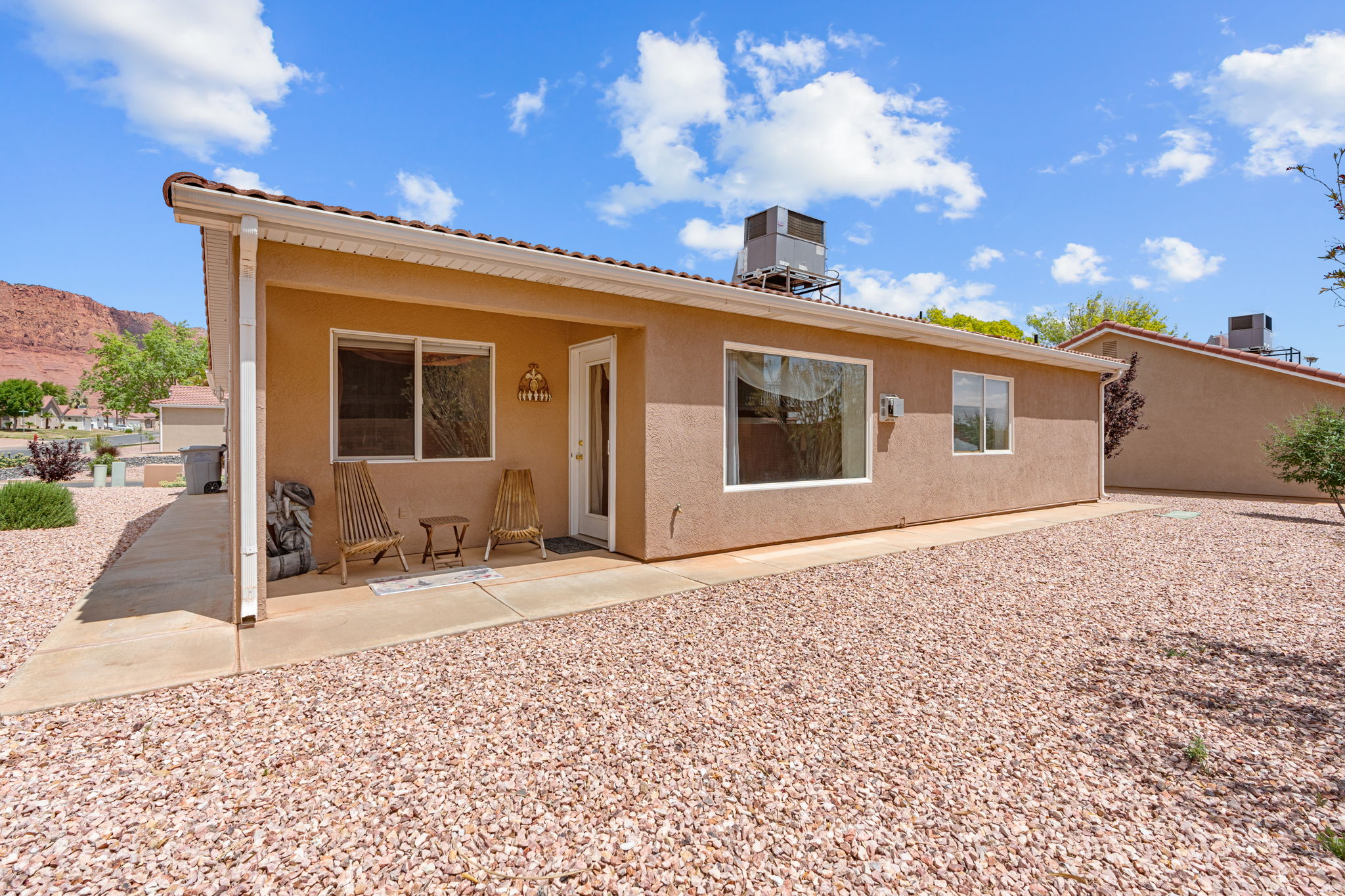 Stucco exterior with a covered patio and a rock landscape