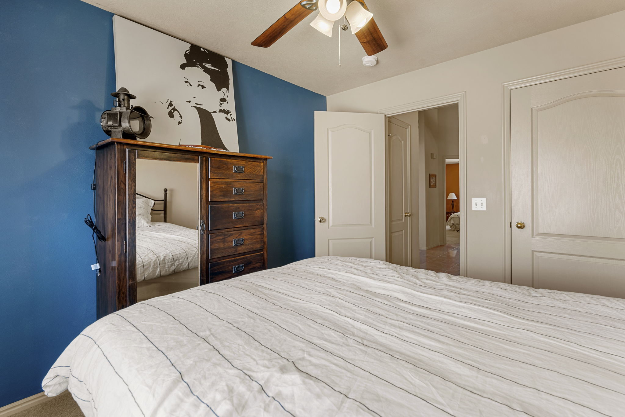 Interior room featuring a ceiling fan with light fixture, two panel-style doors, and a blue accent wall