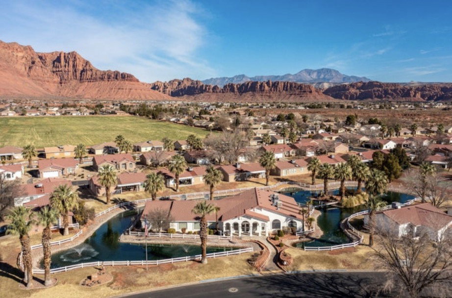 Architectural complex featuring a red tile roof, multiple residential structures, and extensive water features with fountains