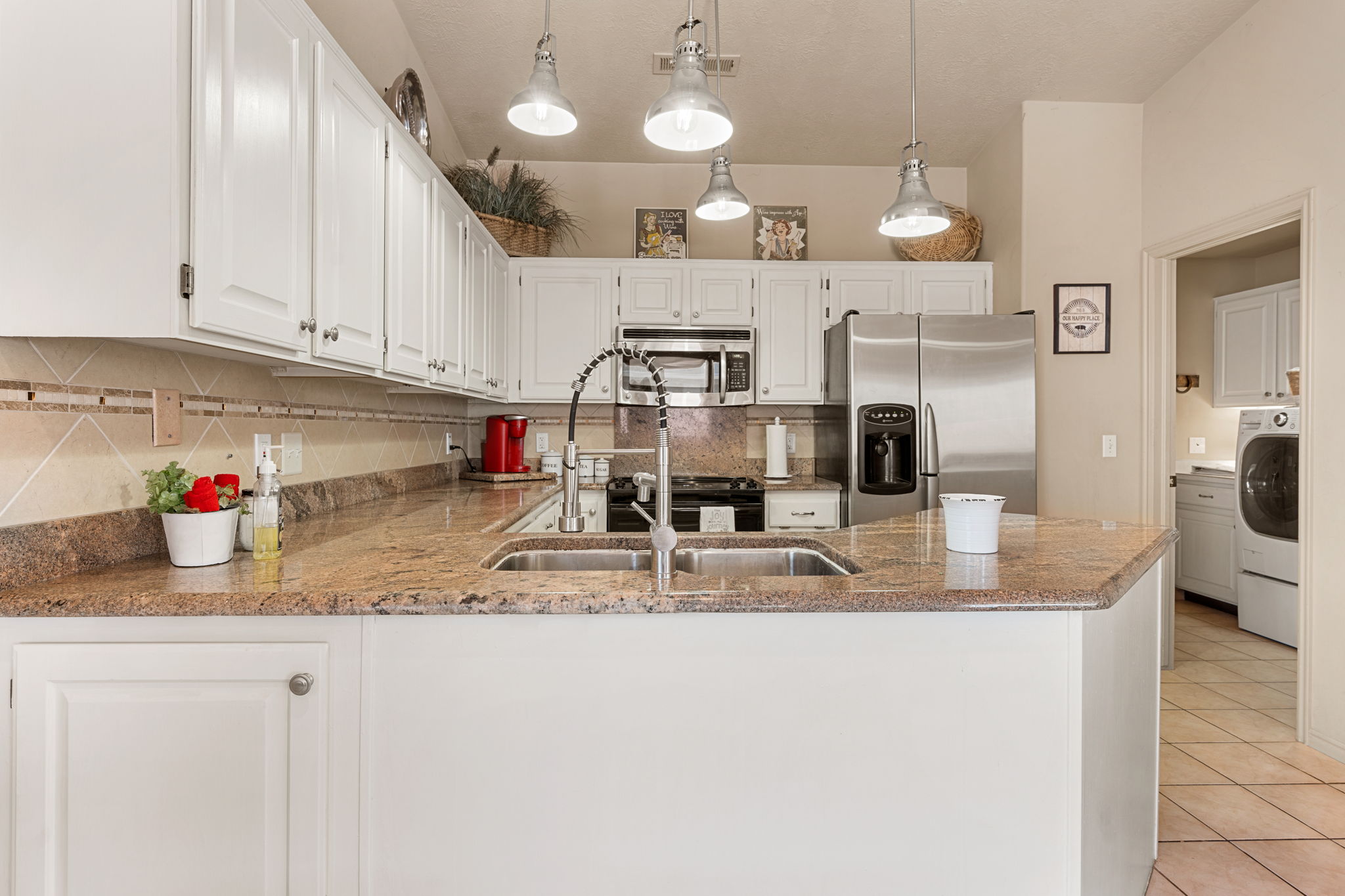 Kitchen featuring granite countertops, white cabinetry, a built-in microwave, a stainless steel refrigerator, and dual basin sinks