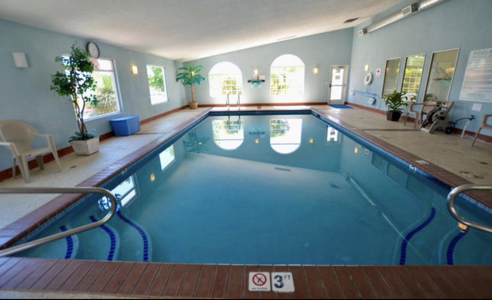 Indoor swimming pool featuring an arched window, multiple rectangular windows, and a sloped ceiling
