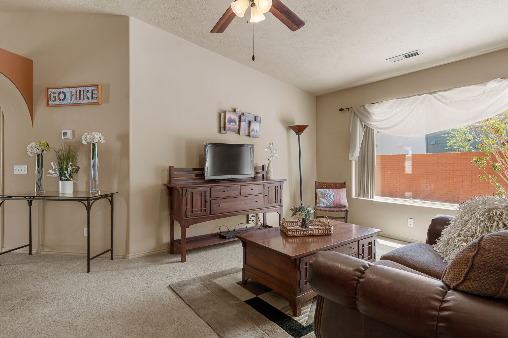 Open living area with neutral wall tones and a ceiling fan