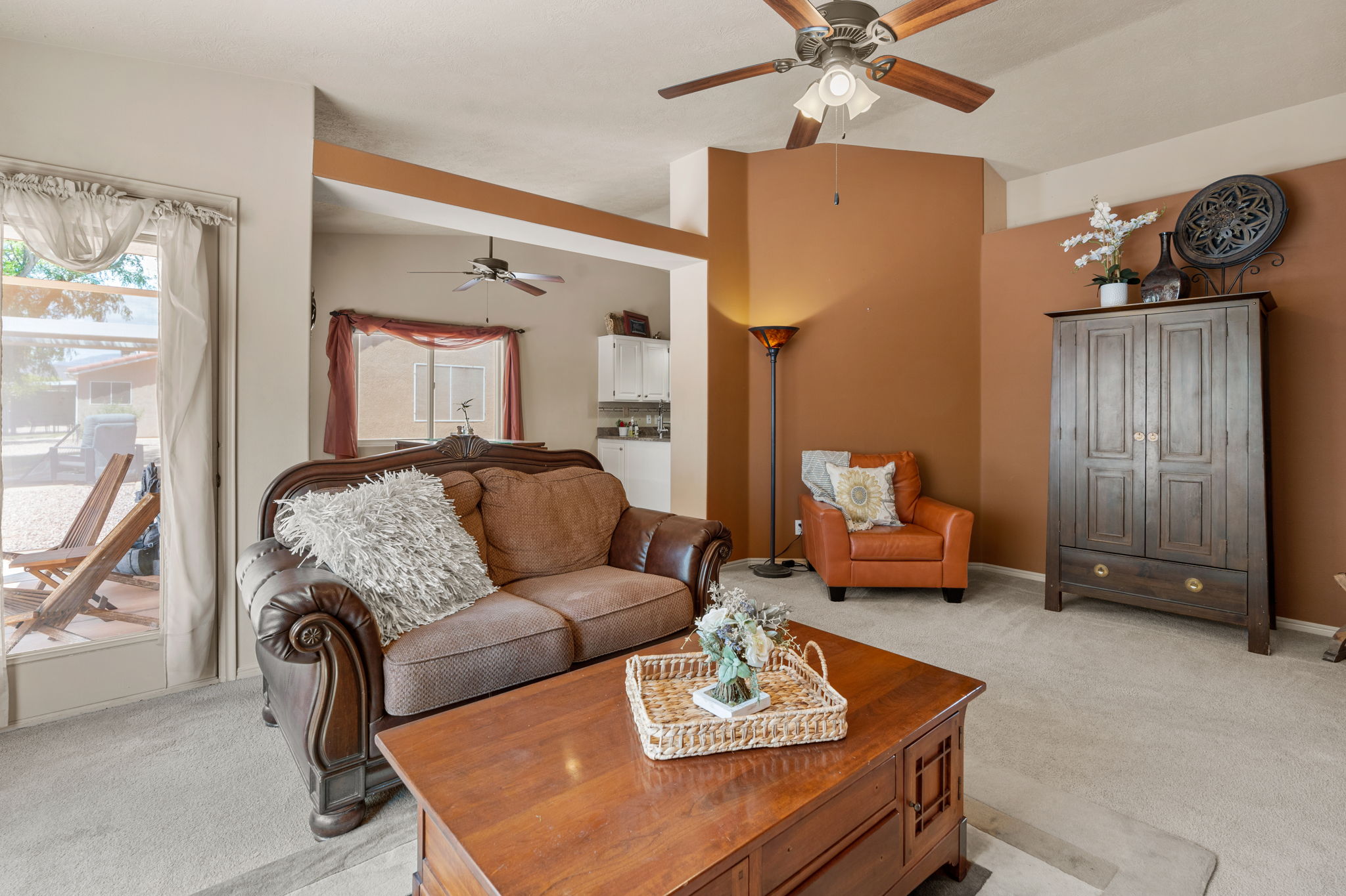 Spacious living area featuring vaulted ceilings with a ceiling fan, neutral carpeting, and a patio door for outdoor access