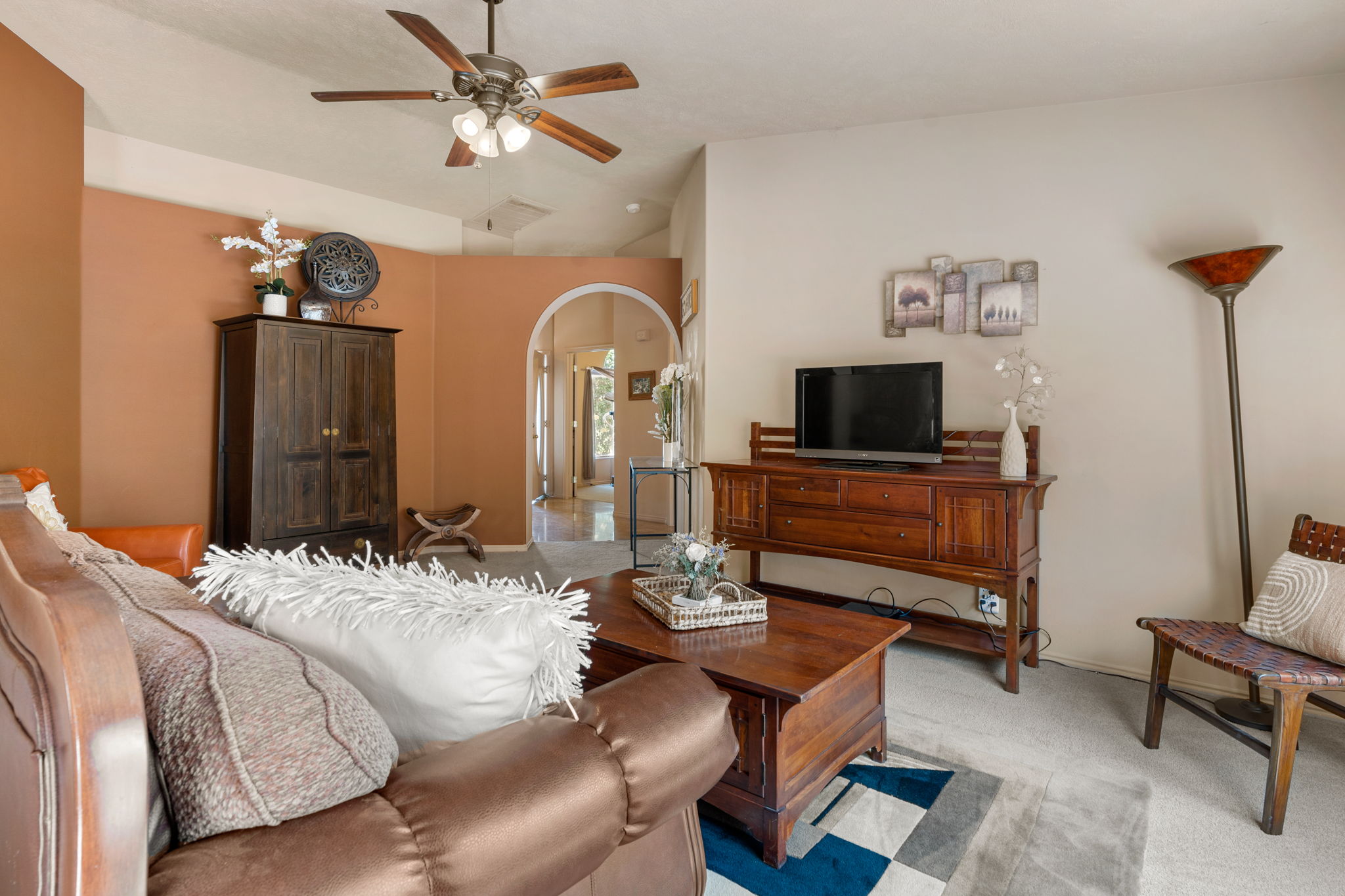 Living area with vaulted ceilings, a ceiling fan with integrated lighting, and neutral carpeting