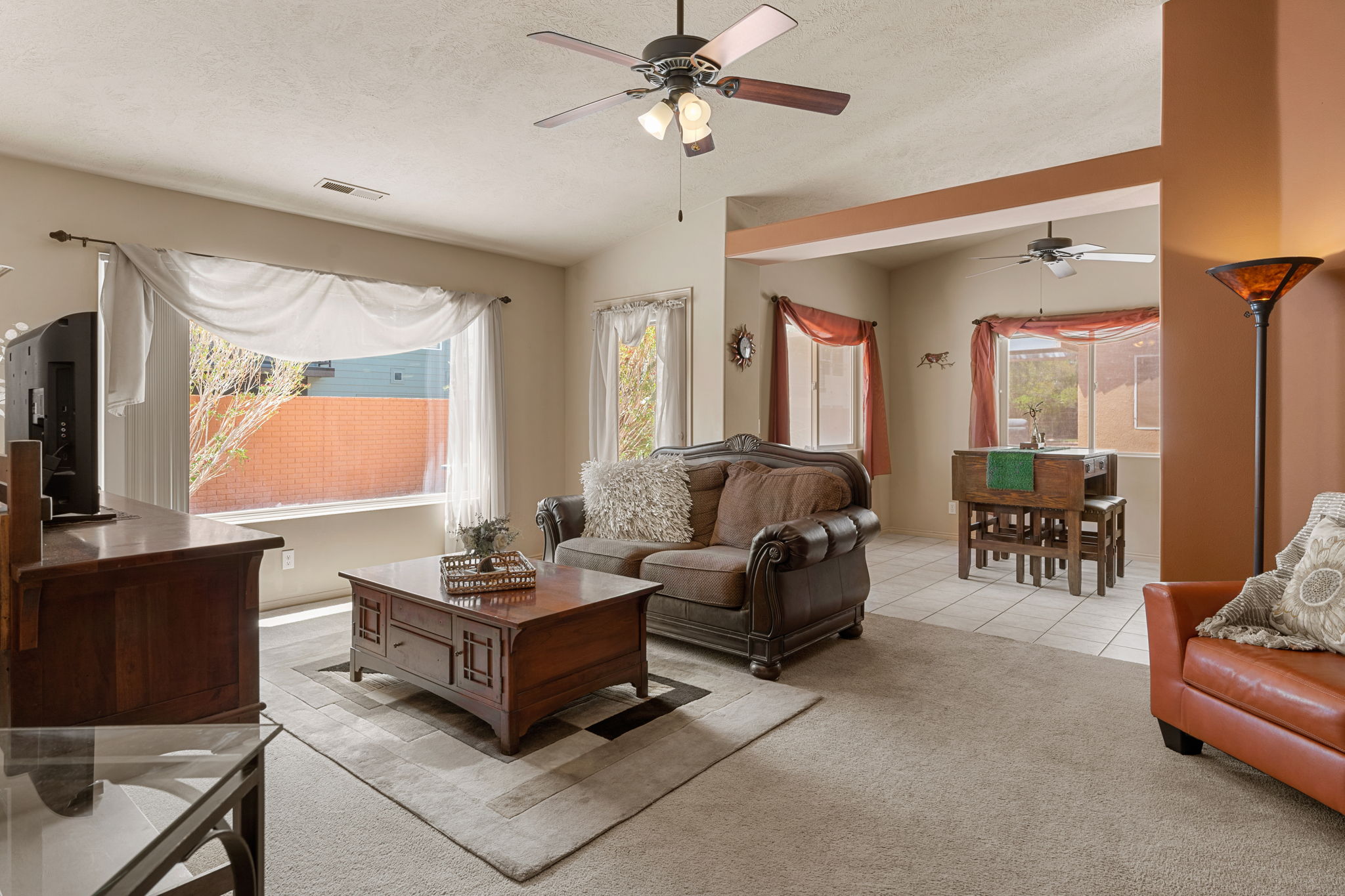 Inviting living space featuring textured carpeting, neutral wall tones, and a ceiling fan with integrated lighting