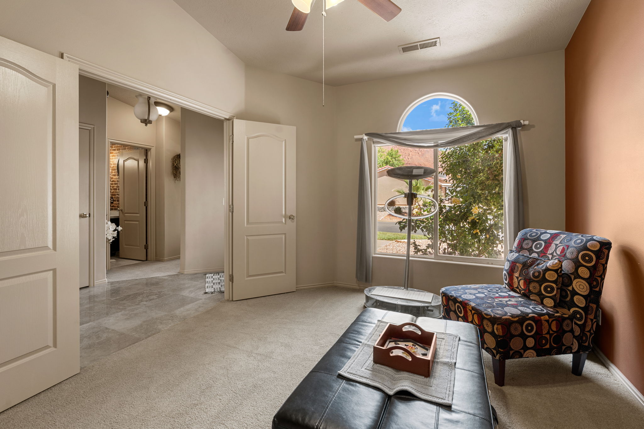 Carpeted room with a large window featuring an arched transom