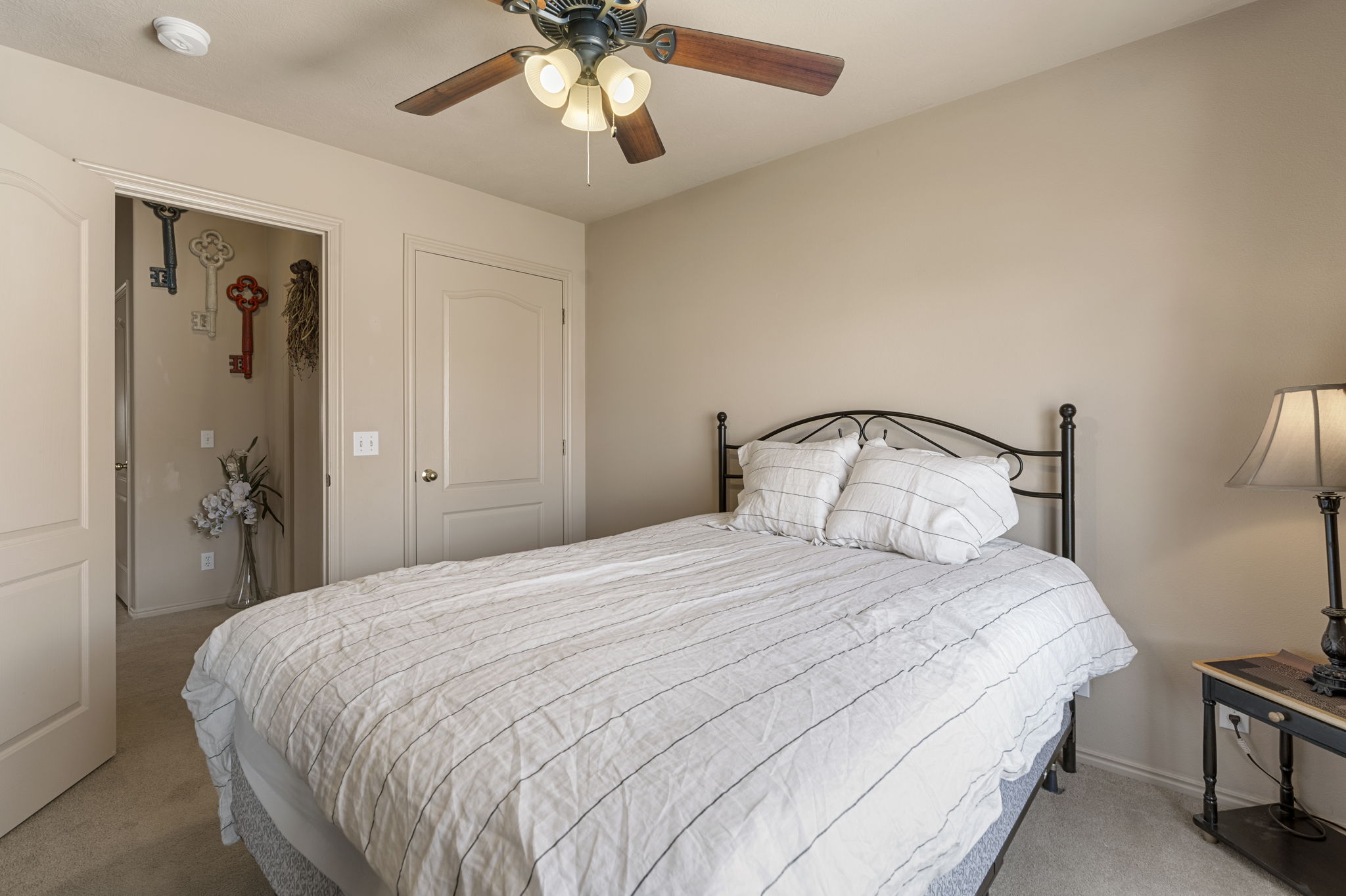 Carpeted bedroom featuring a ceiling fan with integrated lighting, two panel doors, and neutral wall tones