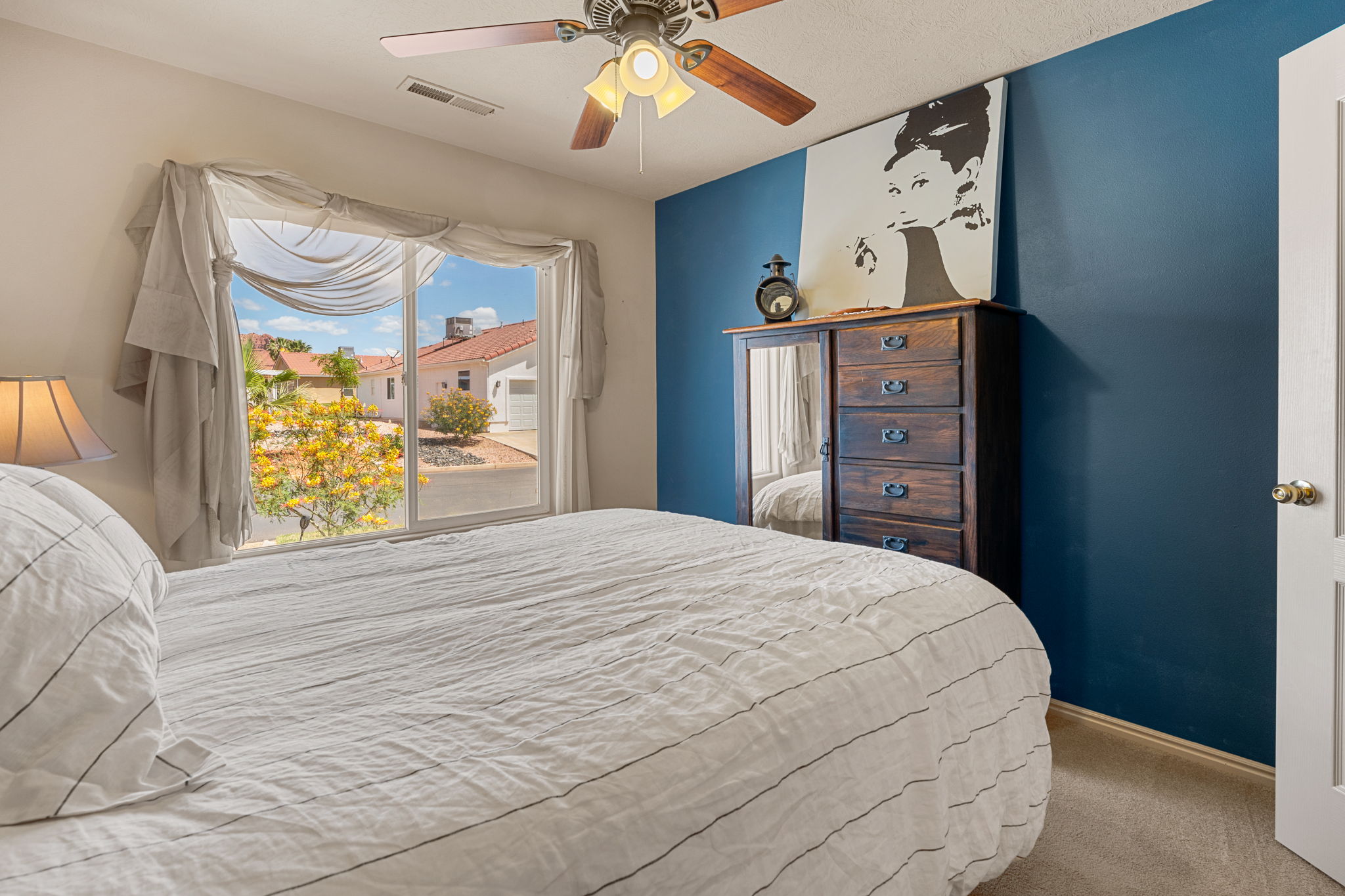Bedroom featuring a large window, ceiling fan with light fixture, and carpet flooring