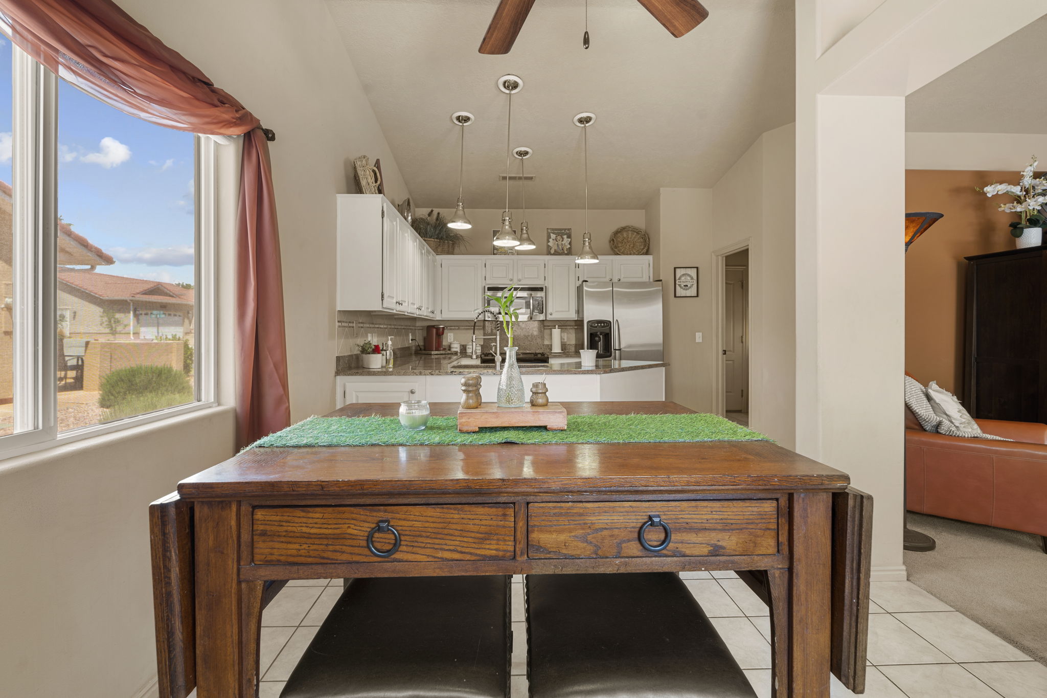 Kitchen and dining area featuring white cabinetry, stainless steel appliances, a tile backsplash, and a wood-finish dining table