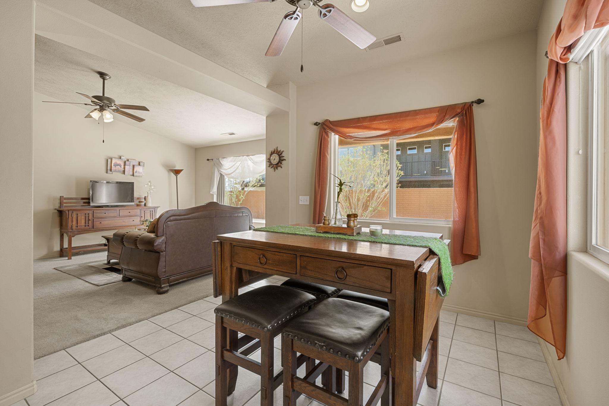 Open-concept dining and living areas featuring a breakfast bar with drop-leaf extension, tile flooring in the dining area, and carpeted living space