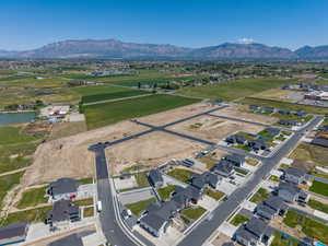 Developing residential area with mountain backdrop, established road infrastructure, and surrounding agricultural land
