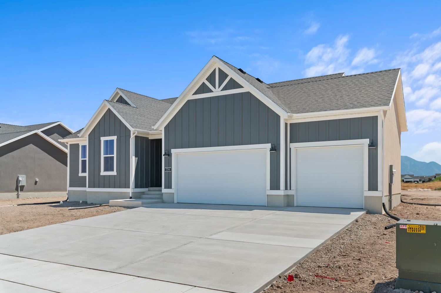 Contemporary ranch-style home featuring gray vertical siding, white trim accents, a concrete driveway, and a two-car garage