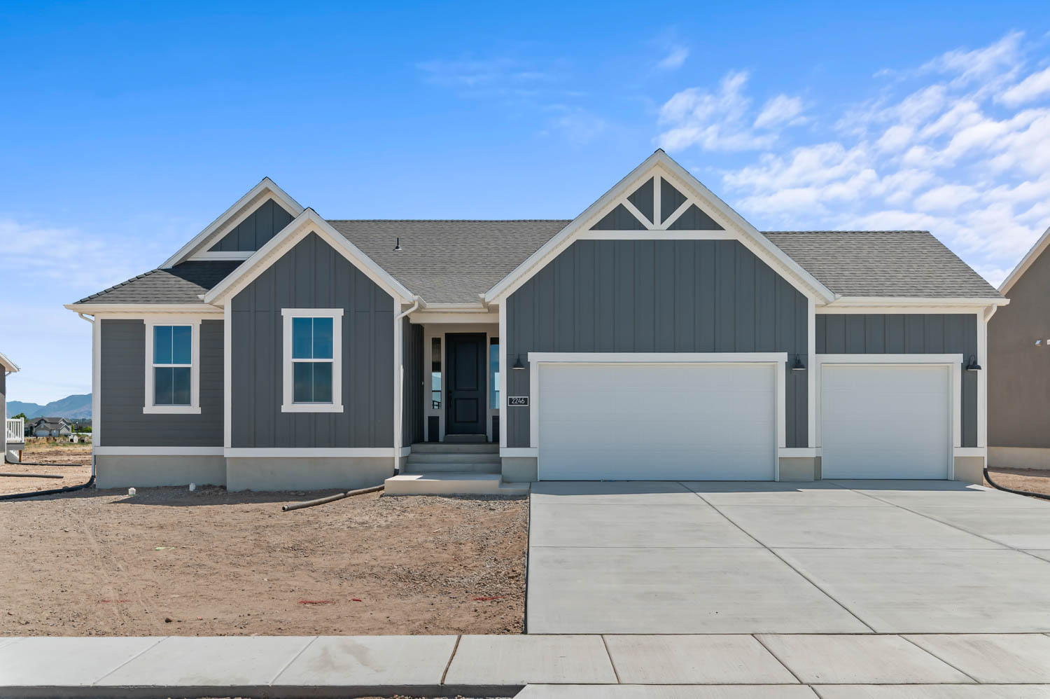 Contemporary ranch-style home featuring a dark gray board and batten facade and white trim accents