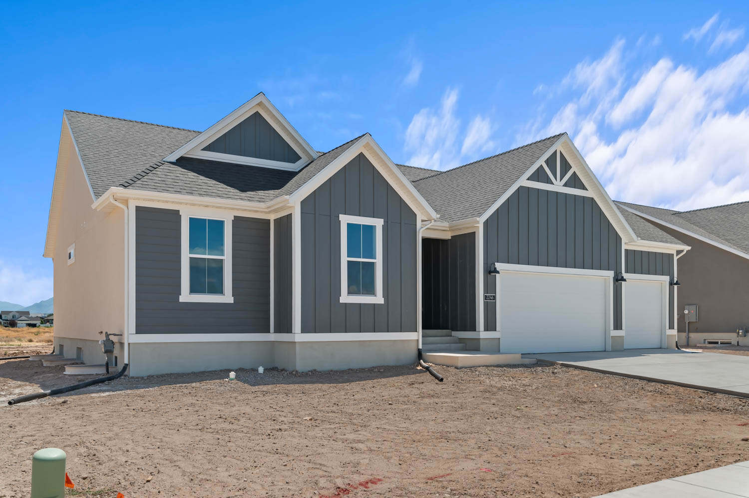 Contemporary ranch-style exterior featuring gray vertical siding, light stucco accents, and a dark shingle roof
